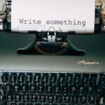 Dark green type writer with "write something" typed onto the page