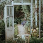 An open greenhouse door leading out into an out of focus path