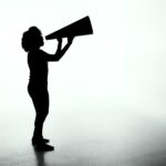 Silhouette of a women yelling into a megaphone.