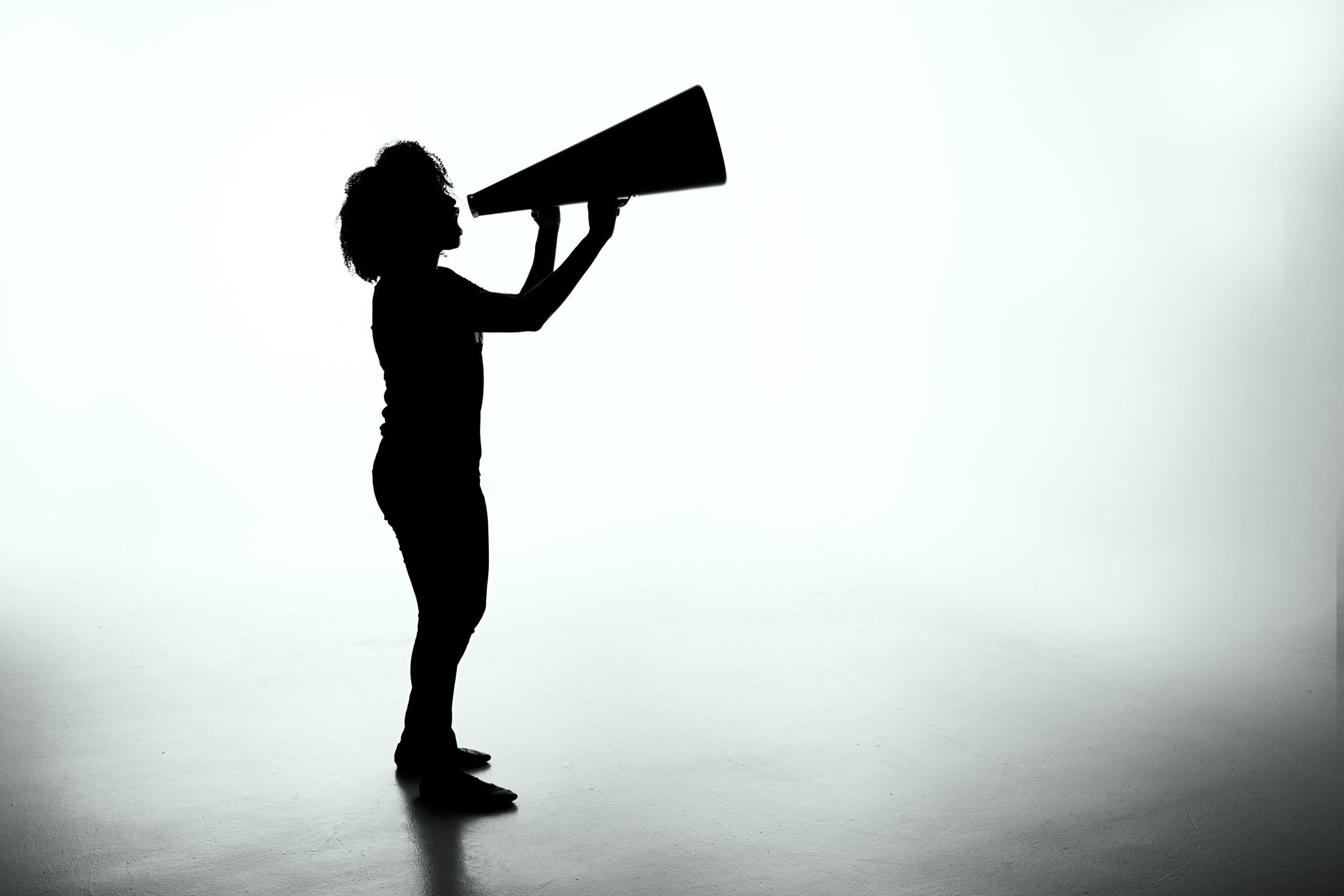 Silhouette of a women yelling into a megaphone.