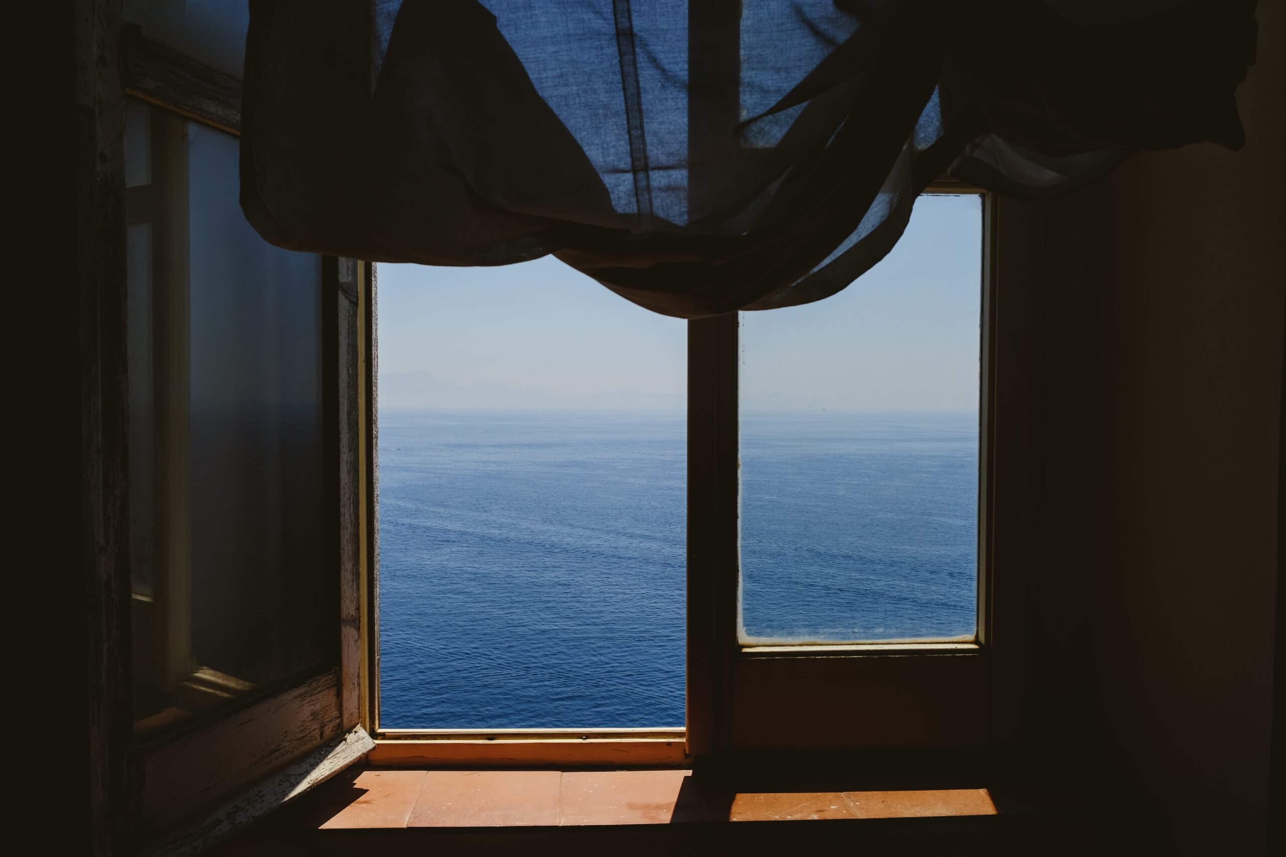 Black window curtain on window overlooking water