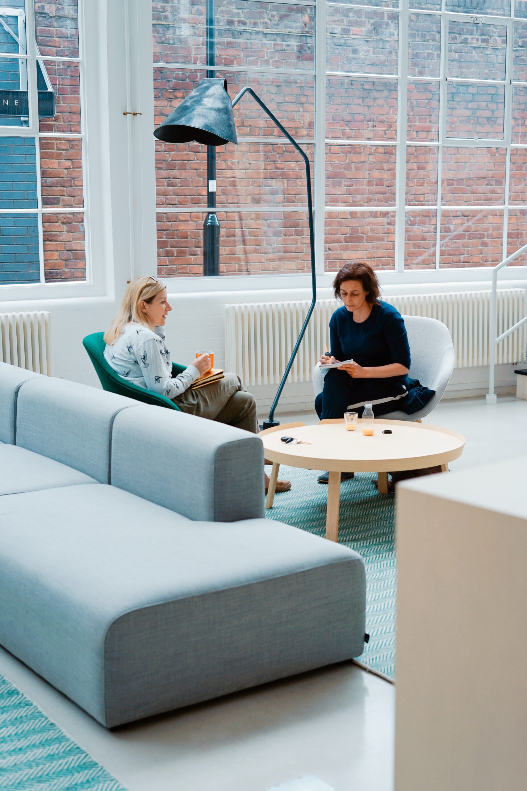 Two women sitting on chairs having a discussion with one another.