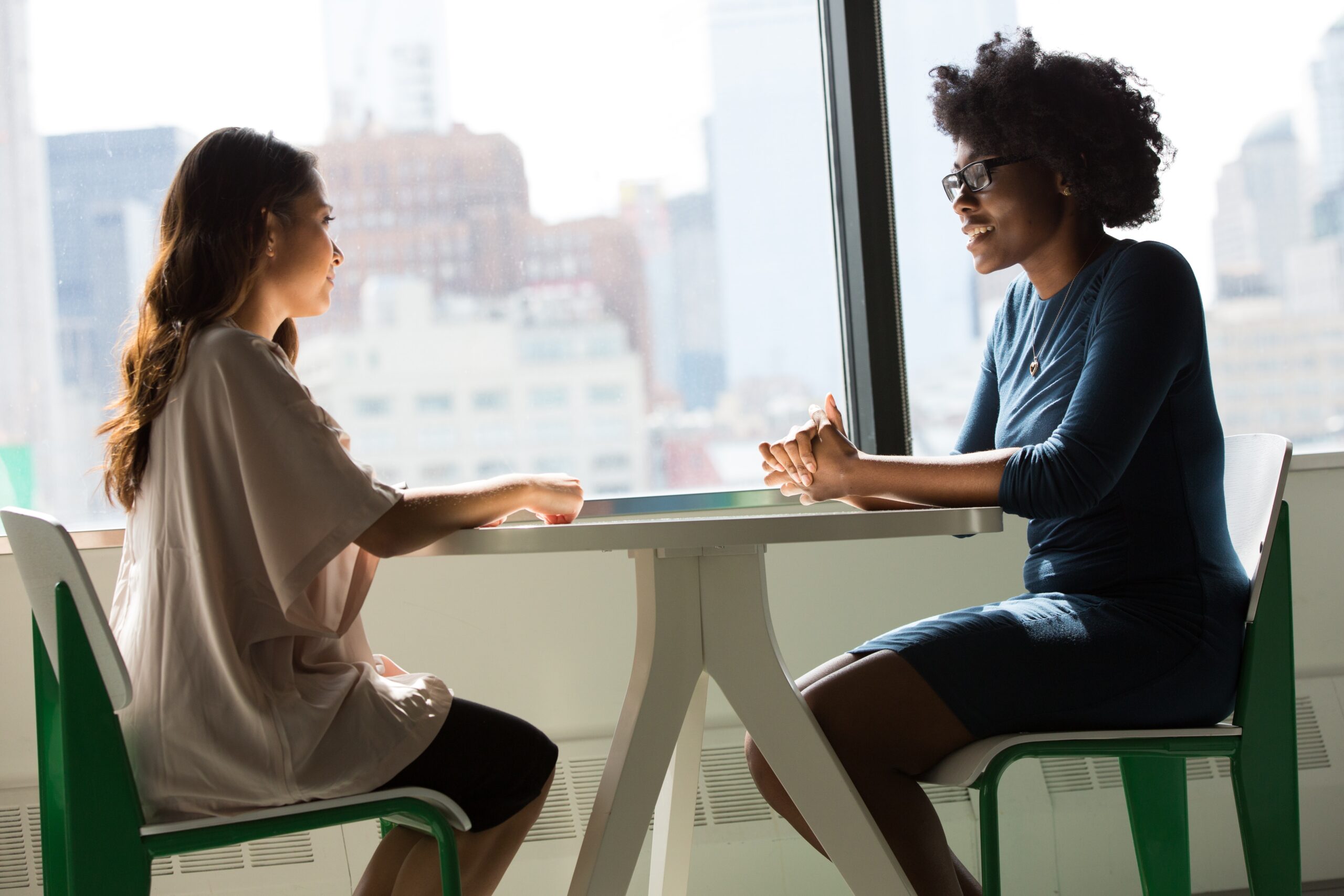 Image of two people sitting down at a table conversing.