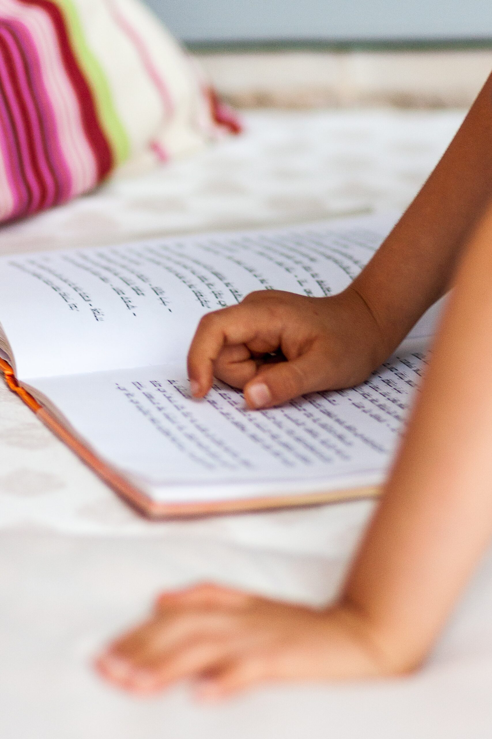 A small hand is traveling across the words of a book.