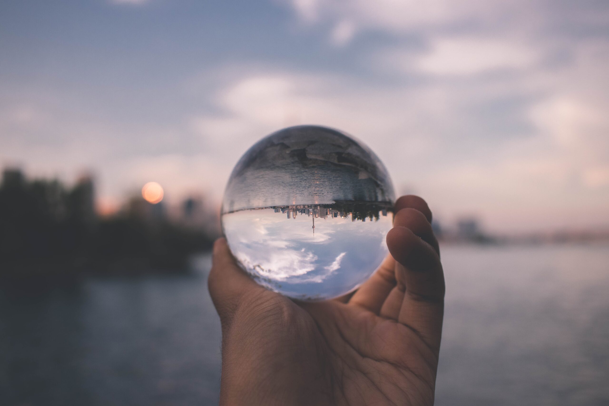 Image of glass ball being held up to the city. The city is shown upside-down in the glass ball.