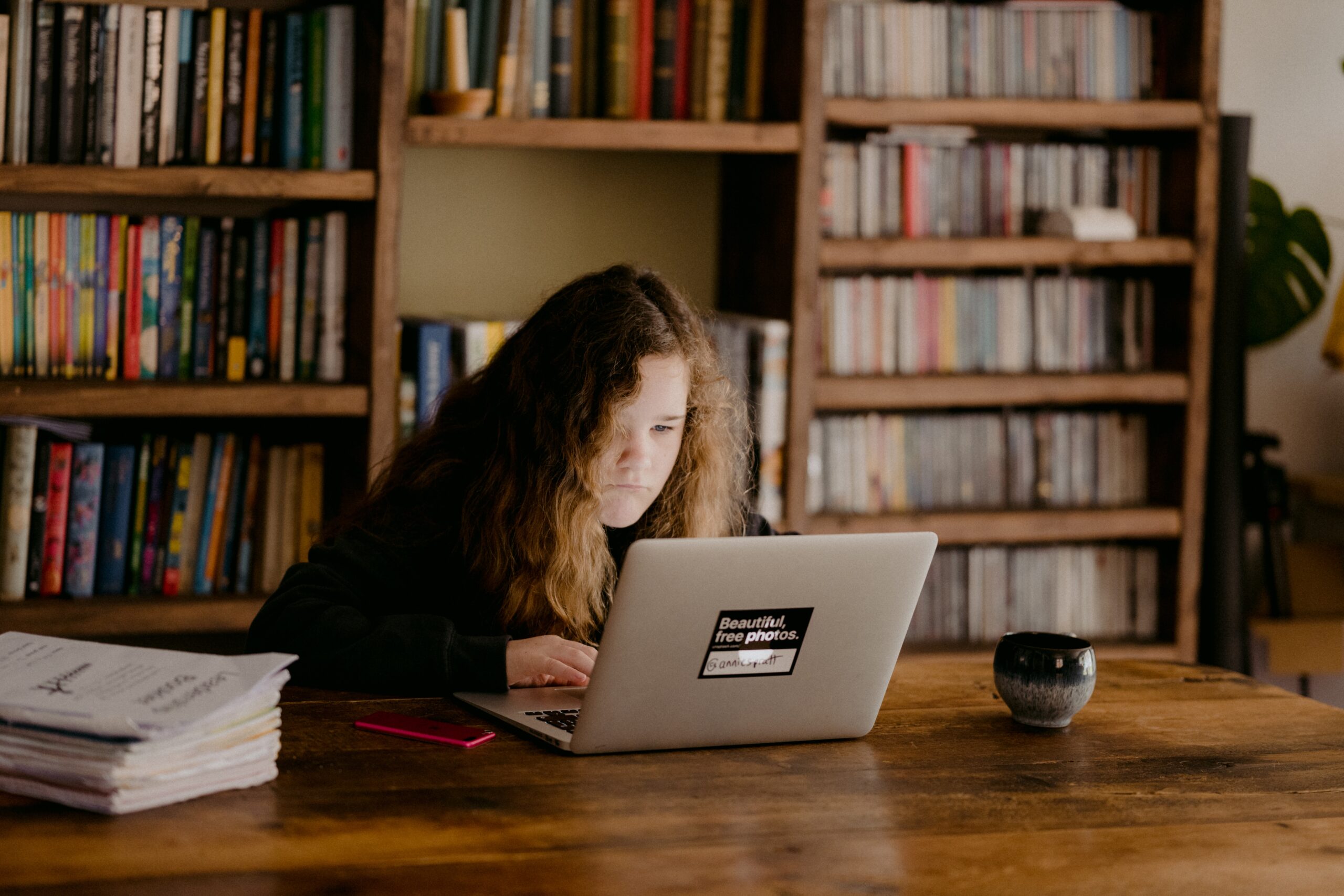 A woman sits hunched over her laptop.