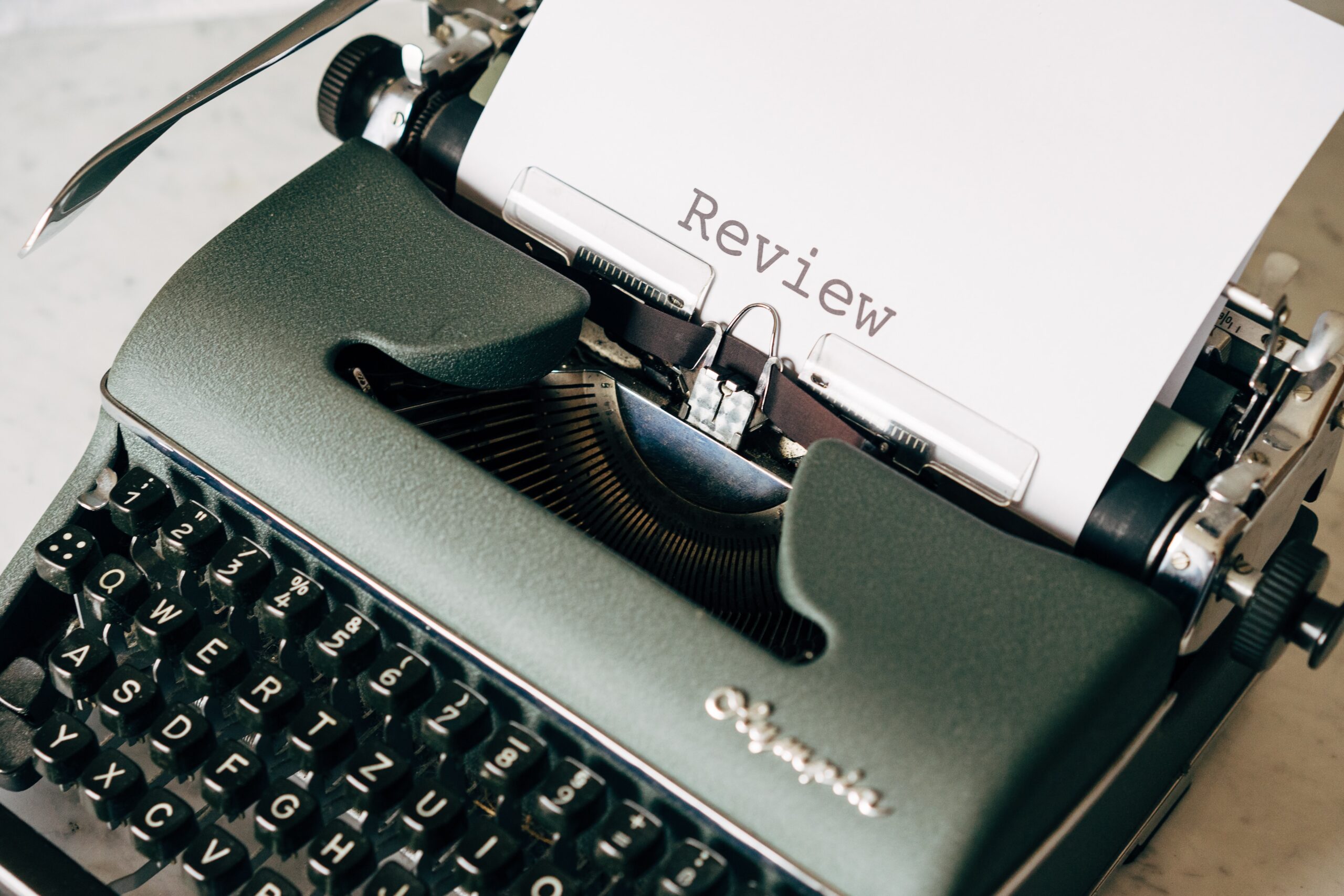 A black typewriter with the word Review printed on a sheet of paper coming out of the top. This is an example of revision.