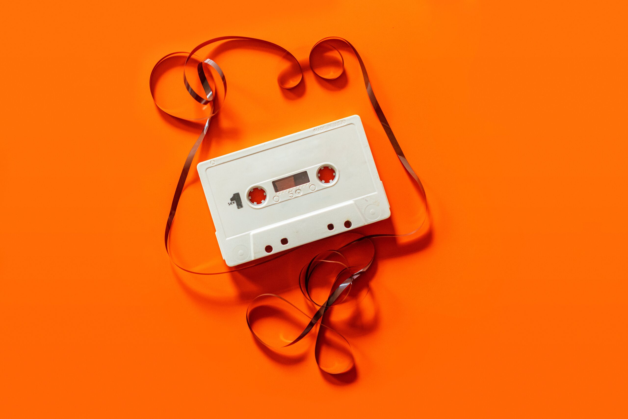 Cassette tape with film unraveled against a bright orange background