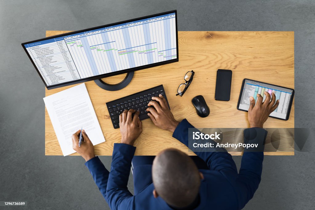 Someone doing many things at once. Typing on a computer, writing and touching a tablet with four arms