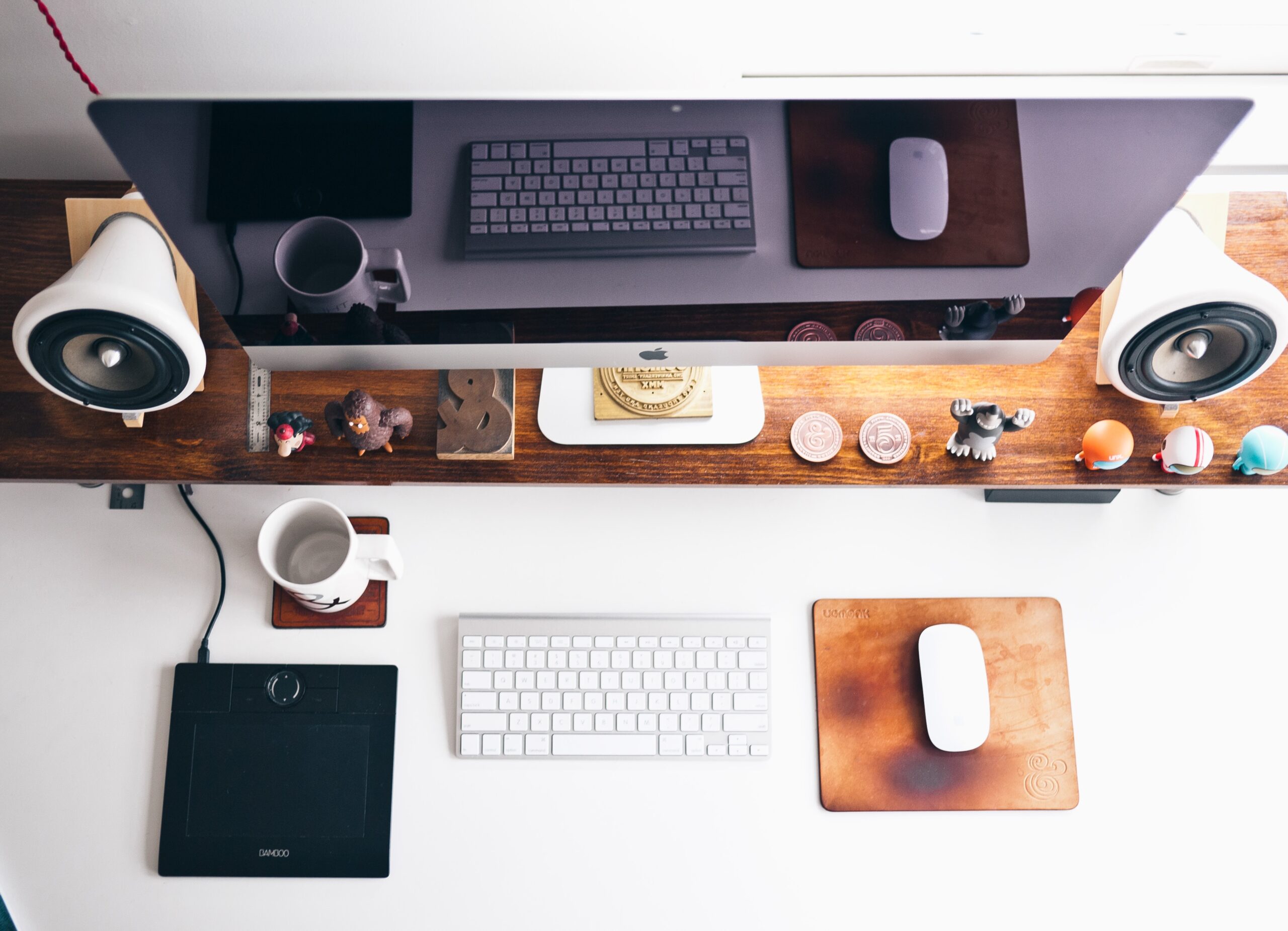 Desk full with office supplies, desktop, speakers, keyboard, mouse.