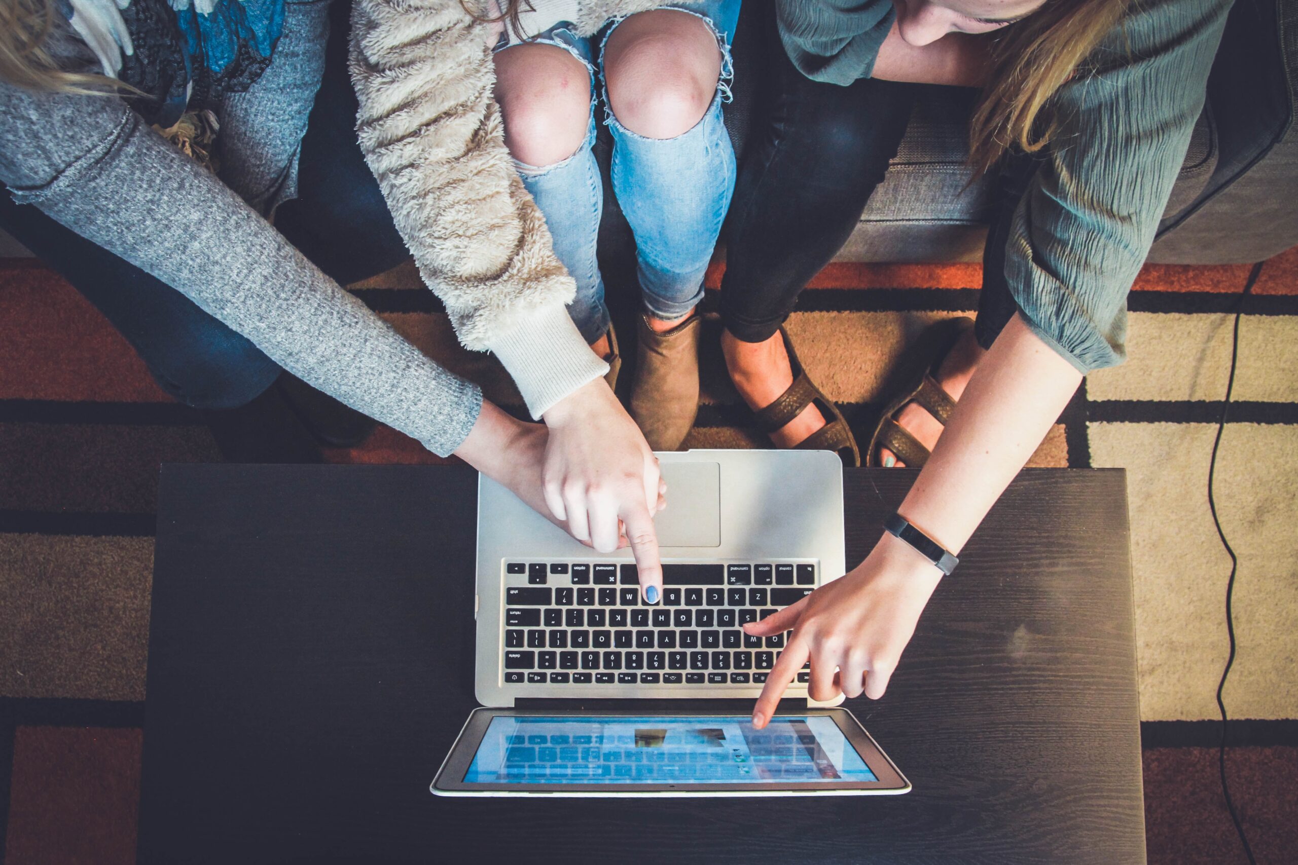 image of three people sitting on a couch and pointing at a laptop screen