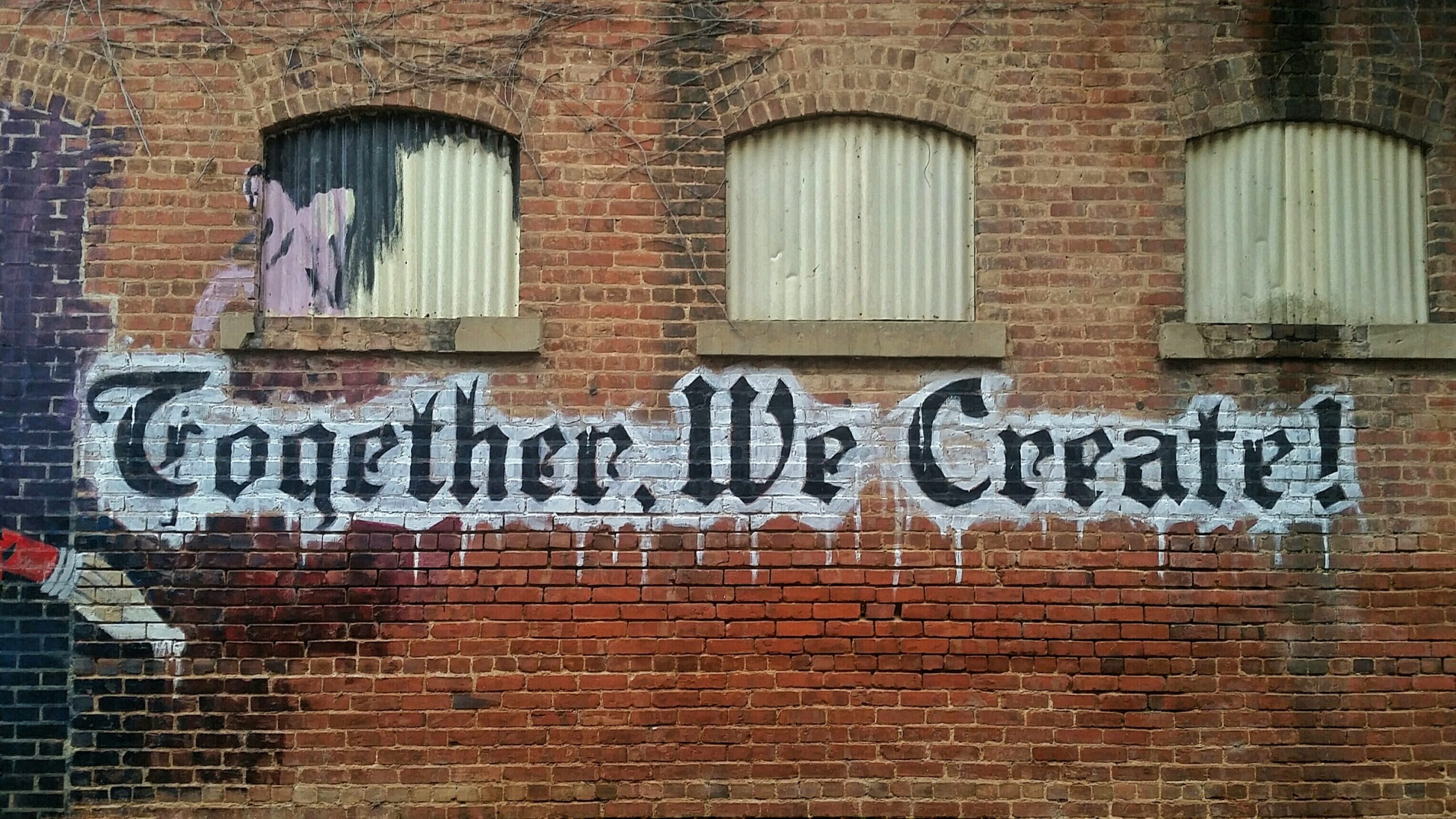 "Together, we create!" on brick wall