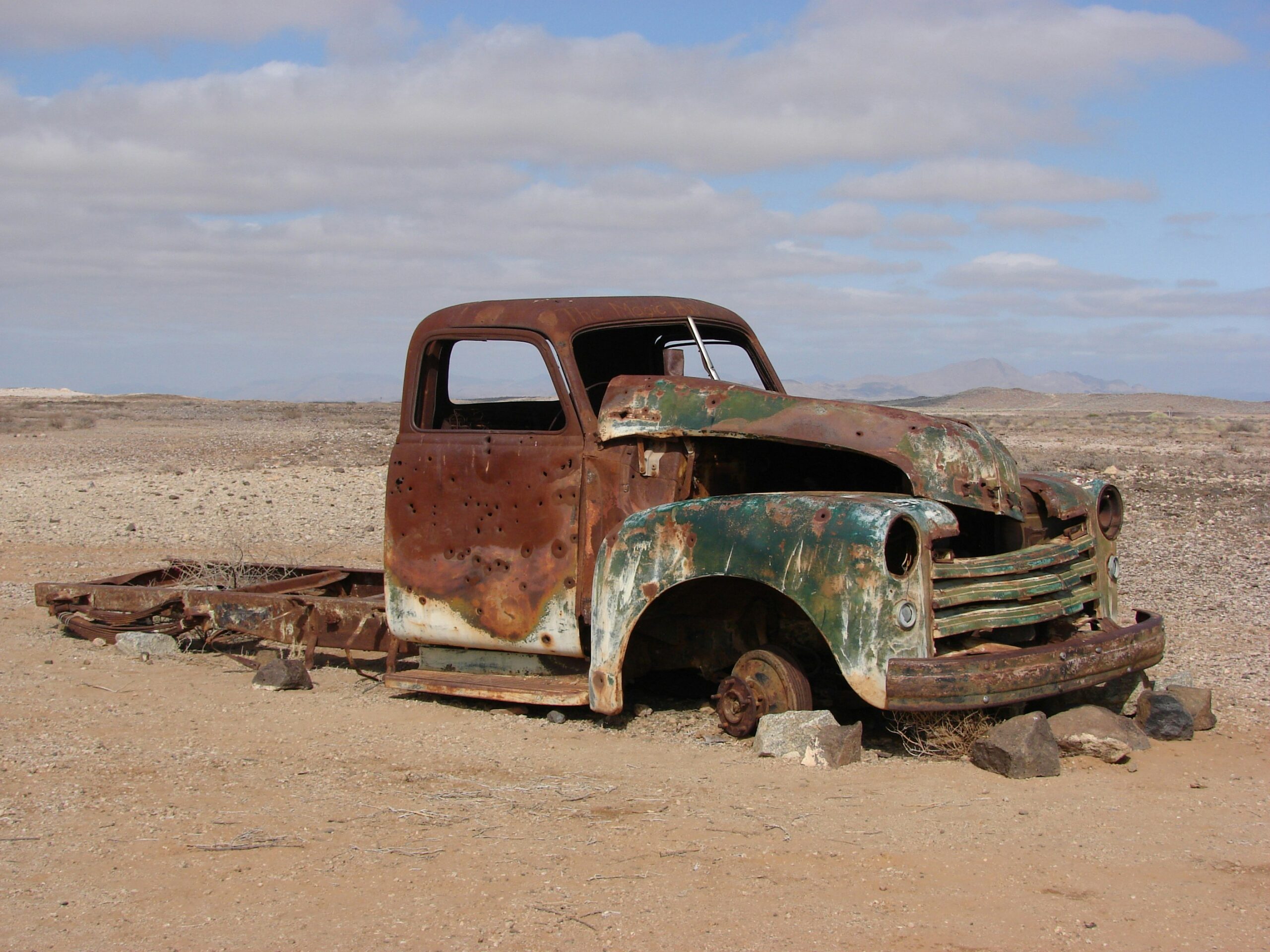 A rusted out vintage truck stuck in sand. It represents stagnation.