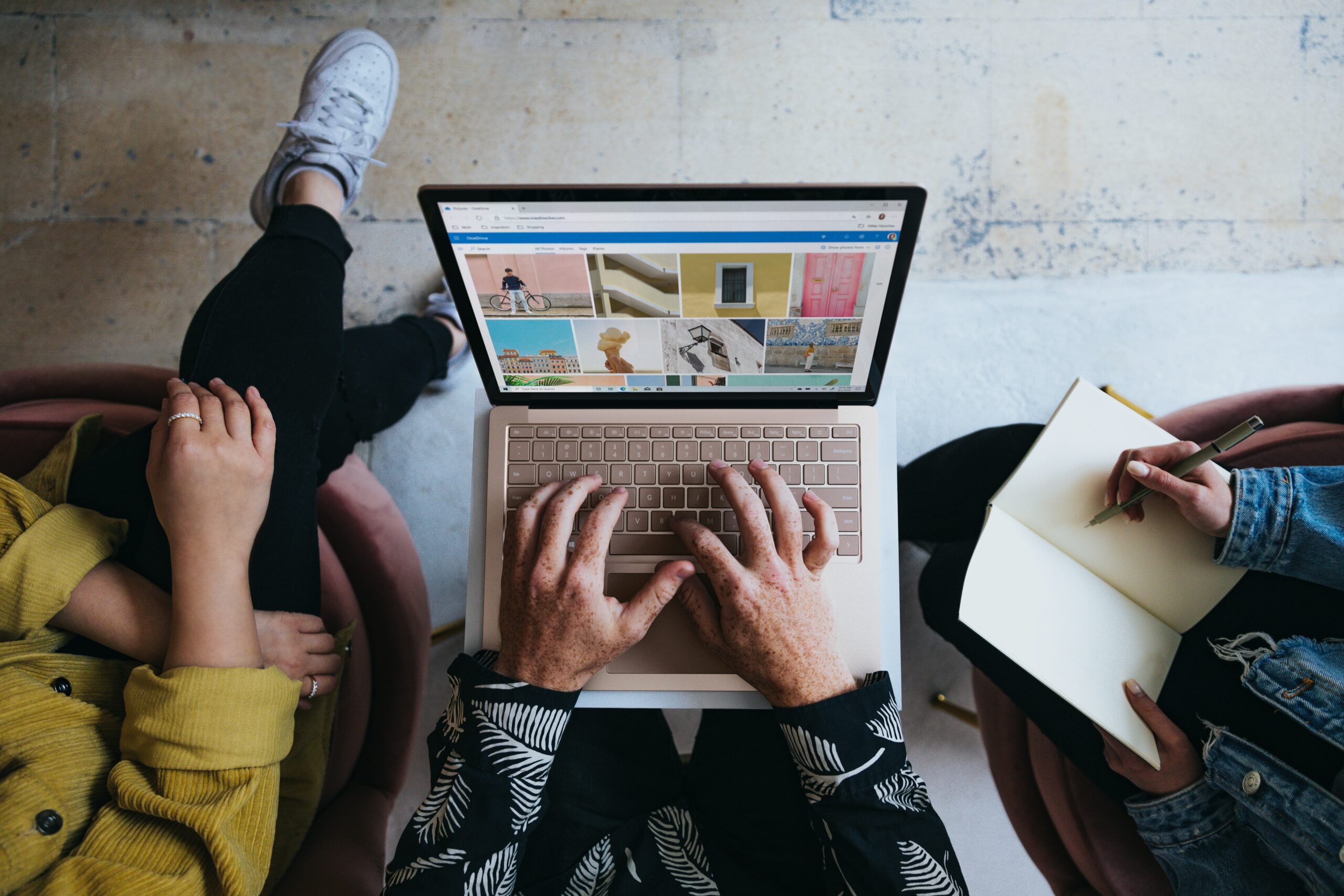 Person using laptop with two other people present