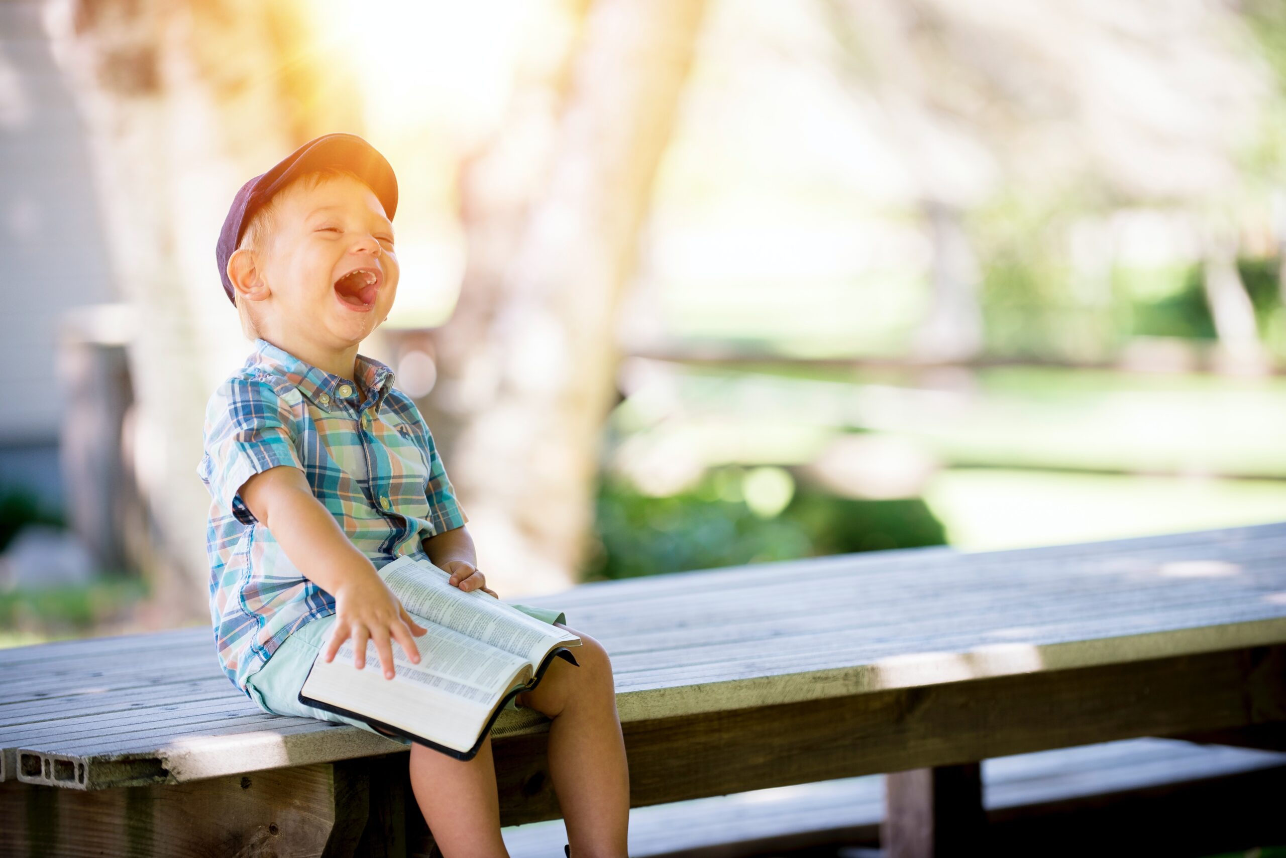 A kid laughing while reading a book.