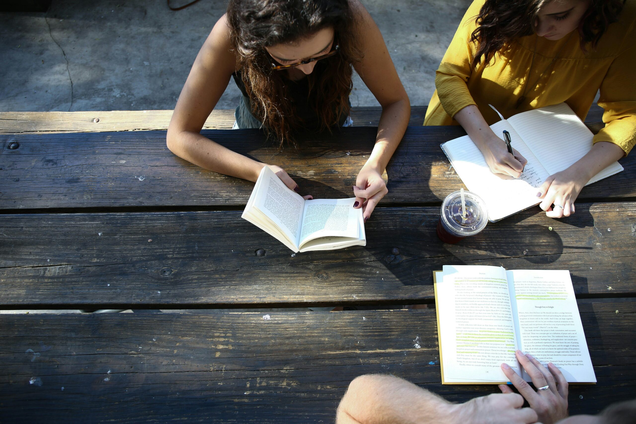 three friends sitting together reading and writing