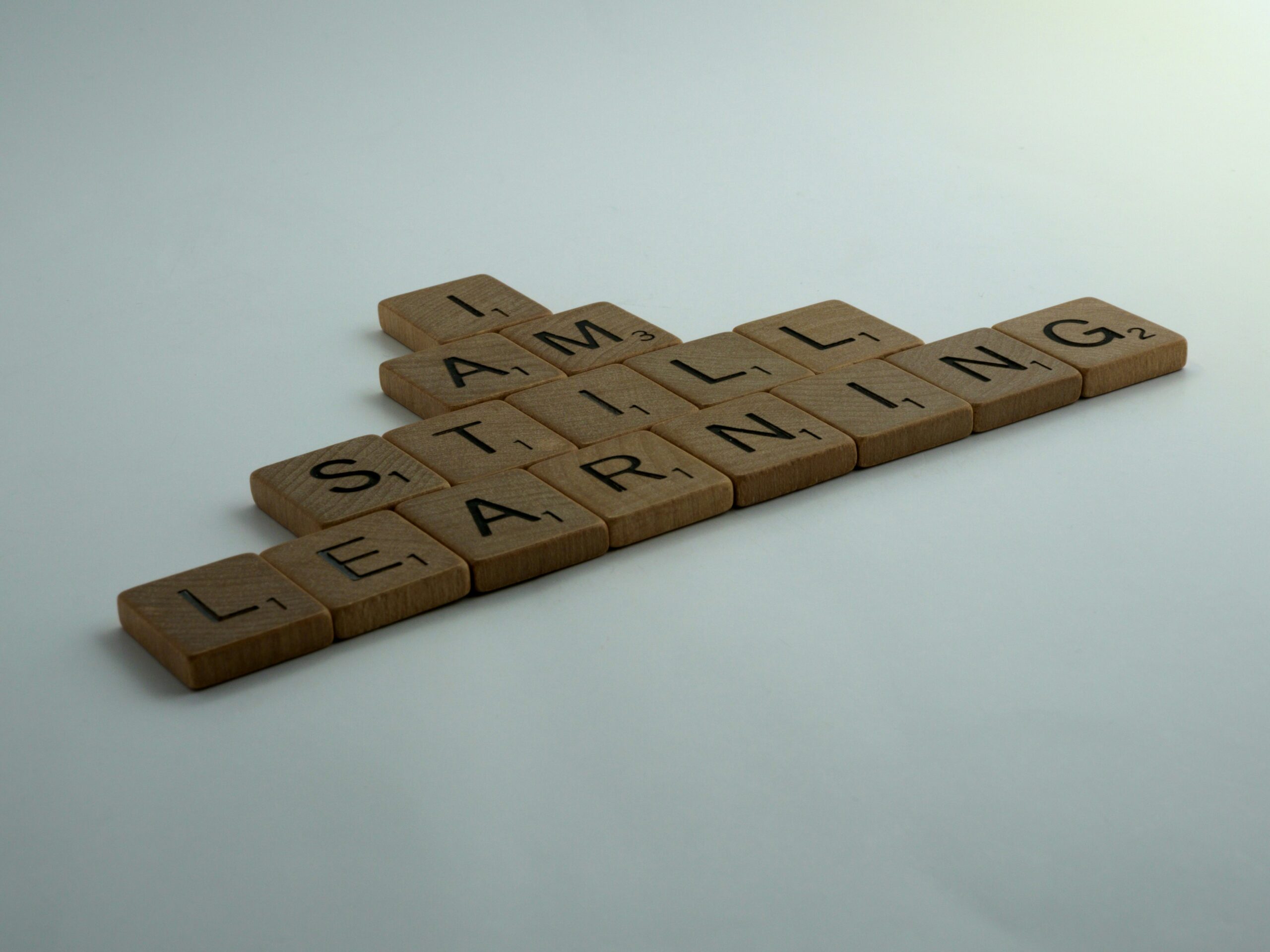 Scrabble pieces are mixed together to form the words "I am still learning."