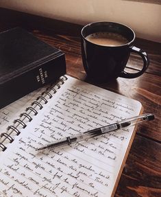 journal lying open on page with writing next to a coffee mug and another book