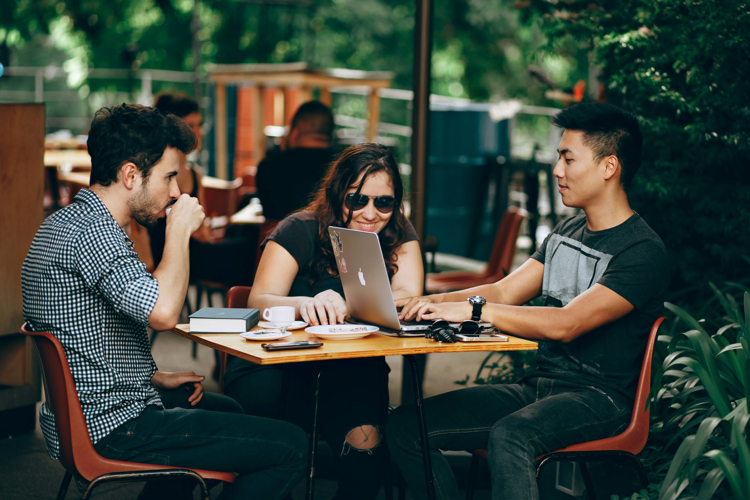 3 people working on group project in coffee shop with laptops