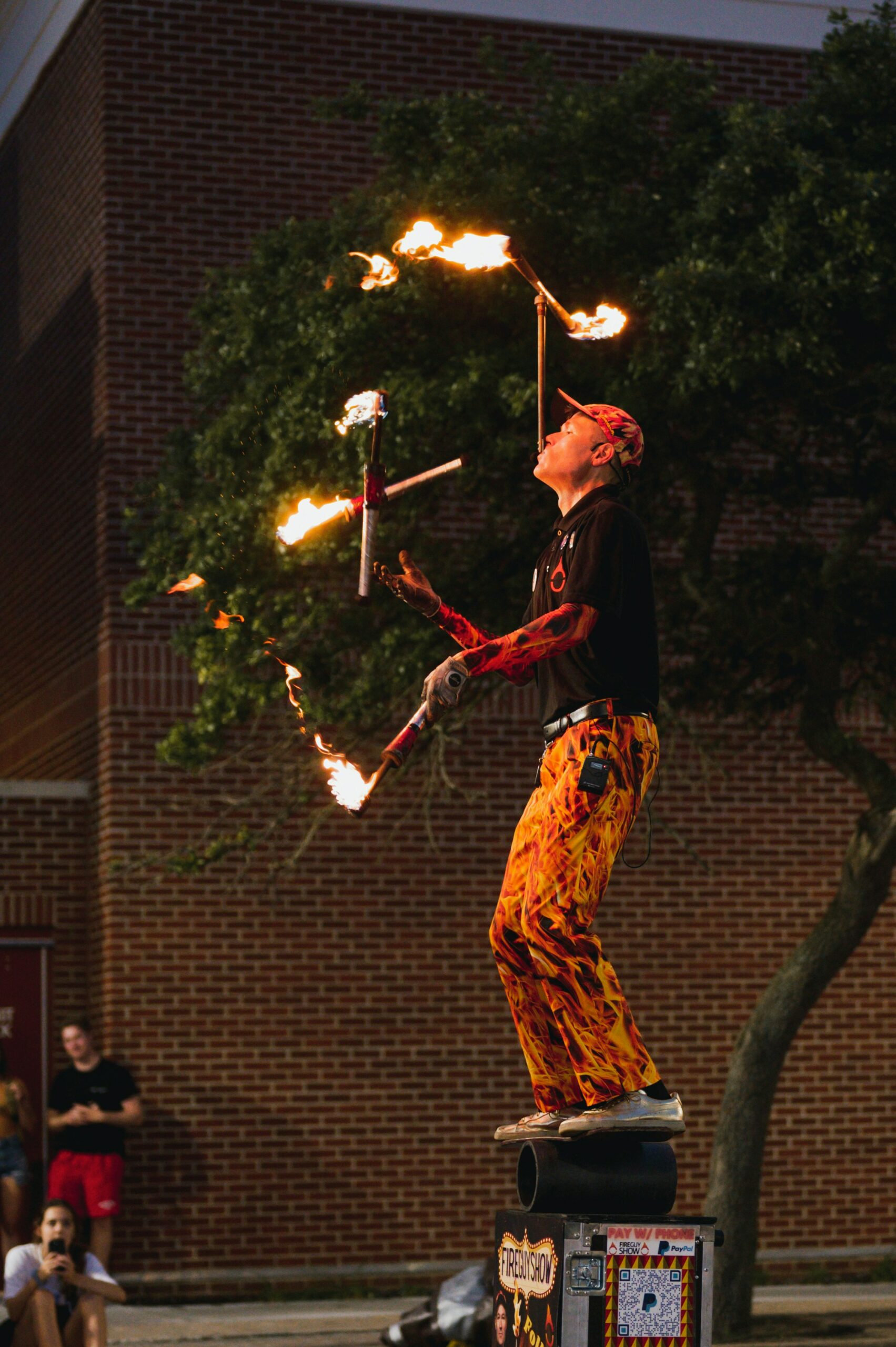 A man juggling fire torches while trying to balance.