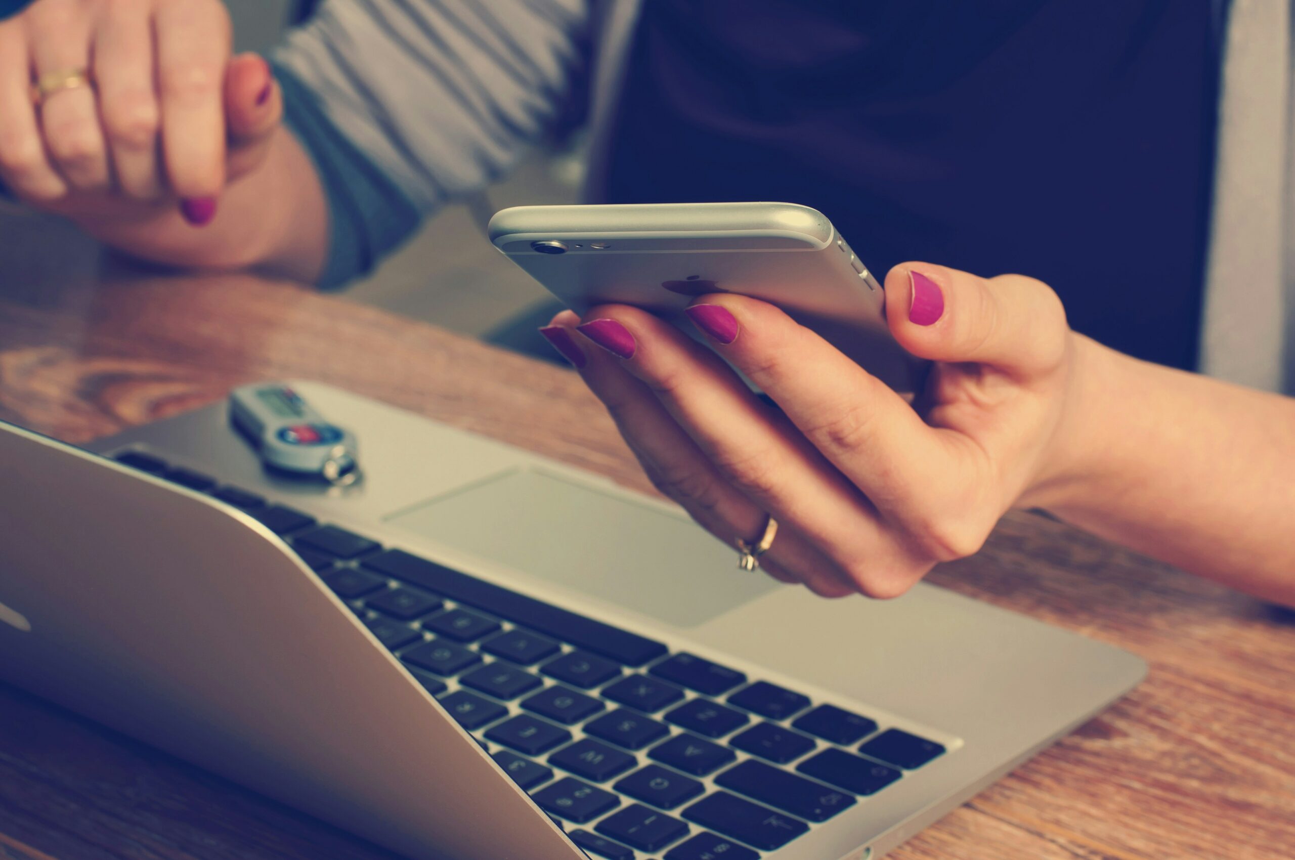 Photo of person holding a phone while also on a laptop.