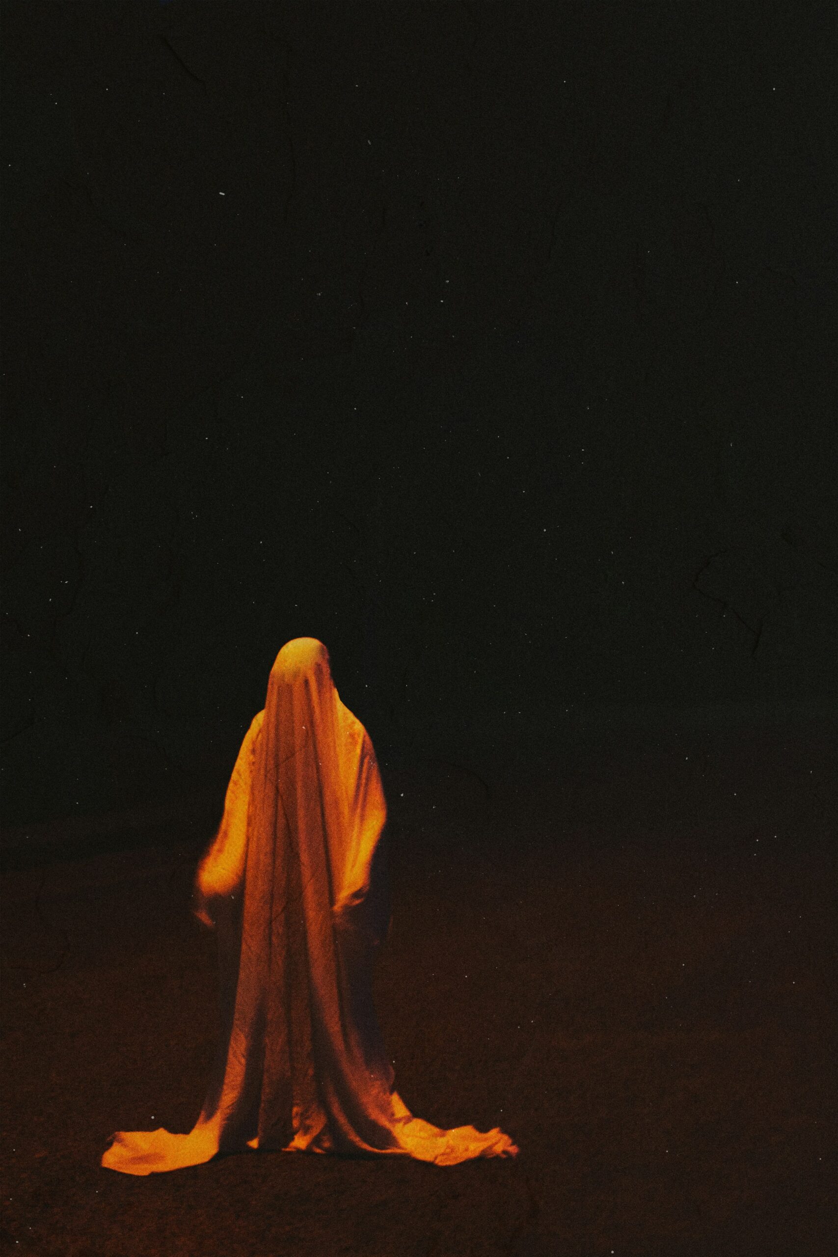 Person in yellow hijab standing in brown field at night