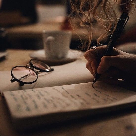 Glasses on notebook while a person writes.