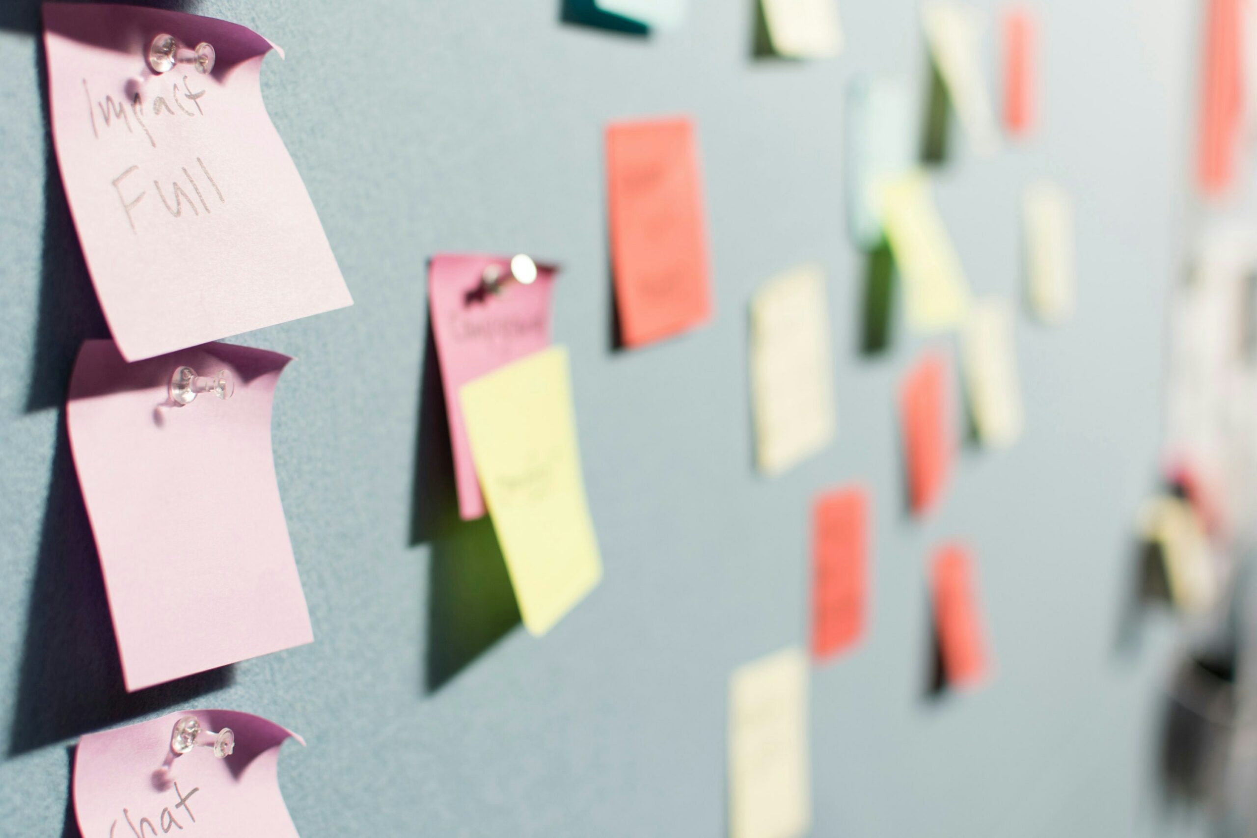 Various colored post it notes on a board, with one word in focus saying, "Impact / Full"